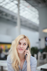 beautiful girl talking on the phone sitting in a shopping center, business center