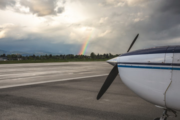 Front view of the airplane propeller with beautiful clouds and rainbow in the background. Taken in Pitt Meadows Airport, BC, Canada.