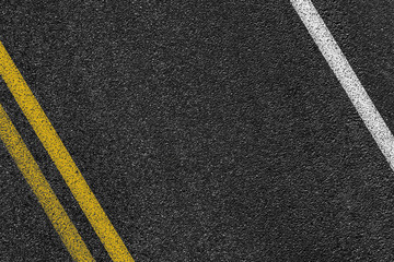 Level asphalted road with a dividing white and yellow stripes. The texture of the tarmac, top view. - obrazy, fototapety, plakaty