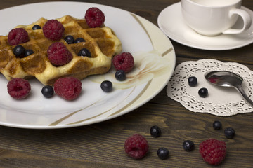 waffles in a white plate with berries on the table
