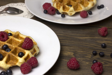 Two plates of waffles and berries raspberries.blueberries