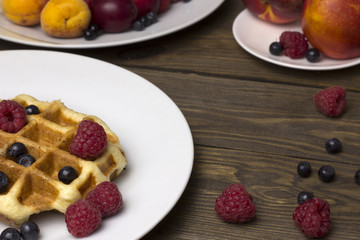 Two plates of waffles and berries on a wooden table