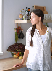 Young woman standing near desk in the kitchen