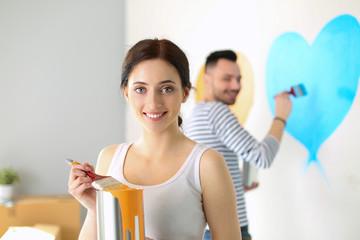 Portrait of happy smiling young couple painting interior wall of new house