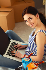 Young woman portrait while painting new apartment ,sitting with laptop