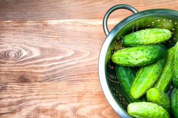 Mini cucumbers in colander on table