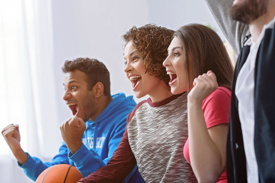 Friends watching sport on TV - Powered by Adobe