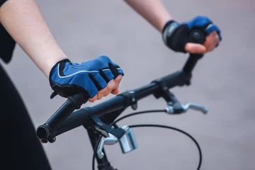 Velvet curtains Bicycles Hands of a girl in a sports blue-black gloves holding on to the steering wheel of the bicycle. Close-up.