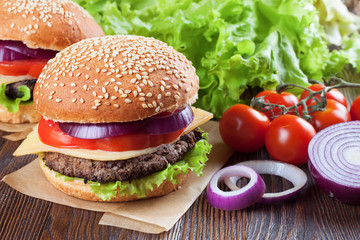 Homemade cheeseburger on brown wooden surface.