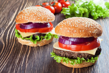Homemade cheeseburger on brown wooden surface.