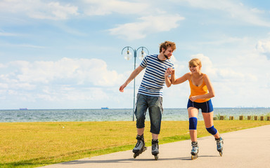 Fototapeta premium Young couple on roller skates riding outdoors