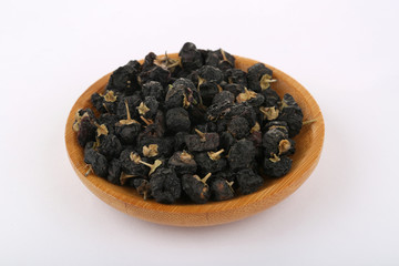 Fototapeta na wymiar Traditional Chinese black herbs dried wolfberry close up on a small plate