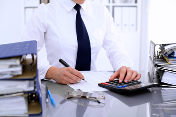 Fototapeta premium Bookkeeper or female financial inspector making report, calculating or checking balance. Internal Revenue Service checking financial document. Audit concept.