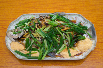fresh steamed whole fish covered with herbs onions and sauce