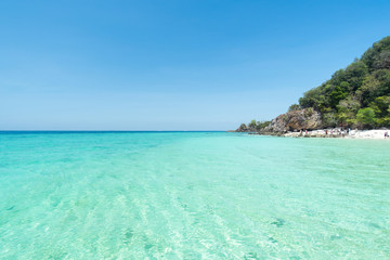 Sea ocean wave on the beach in blue sky with island background.