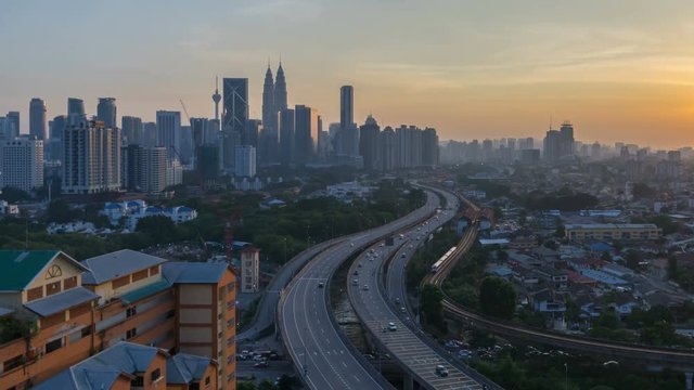 Majestic and beautiful day to night sunset time lapse at Kuala Lumpur city skyline. Showing sky changing colors and light trail from traffic on the road lead to the city. tilt up