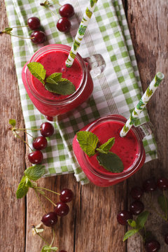 Homemade cherry smoothie with mint in glass jar macro. vertical top view
