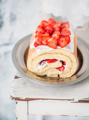 Homemade cake roll with strawberry cream on a white vintage chair