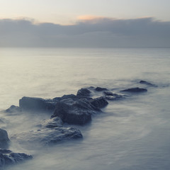 Peaceful cross processed landscape image of calm sea over rocks