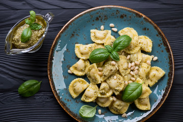 Top view of ravioli served with basil pesto on a turquoise plate