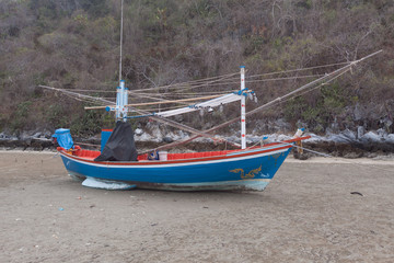 Naklejka na ściany i meble Blue wooden fishing boat on the low tide beach.