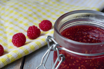 Jar of raspberry jam on the wooden table. Close up