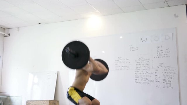Thruster exercise - young athlete doing weight lifting workout at gym
