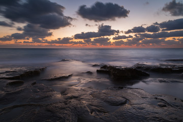 Fototapeta na wymiar Long exposure creating dreamy silky water effect on the rocks after sunset, Nahariya Beach