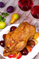 Roasted apple and plum stuffed duck. Glasses of red wine. View from above, top studio shot