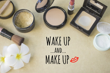 Inspirational quote "wake up and make up" on blurred set of cosmetics background