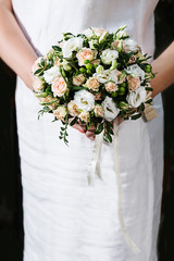 Bouquet of roses in hands of bride in white dress.