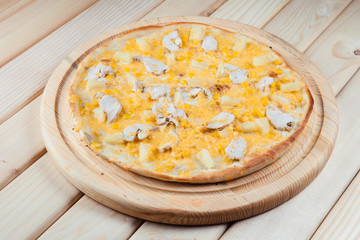 Pizza with pineapple on the wooden background