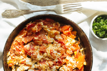 Scramble eggs with tomatoes in pan top view