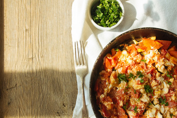 Scramble eggs with tomatoes in pan top view copy space