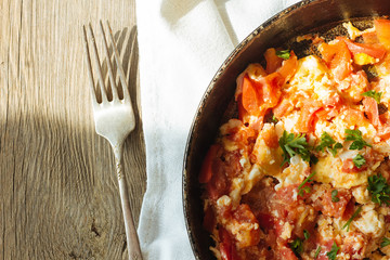 Scramble eggs with tomatoes in pan top view