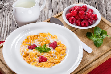 crispy corn flakes with raspberry and milk, close-up