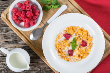corn flakes with raspberry and milk in plate