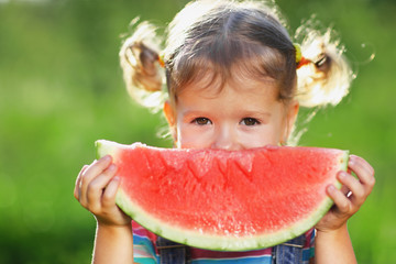 Happy child girl eats watermelon