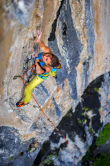 Girl climber climbs on rock.