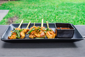 Chicken roast turmeric wrap lemongrass vegetable herb with spicy sour sauce thai food plate cup black in garden