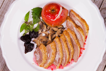Duck breast with apple, smoked plums, mushrooms and basil in red wine sauce. View from above, top studio shot
