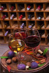 Red, rose and white glasses of wine. Grape, fig, nuts and leaves on old wooden barrel