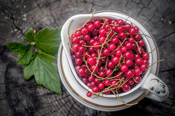 red currant in a vintage bowl on an old wooden background