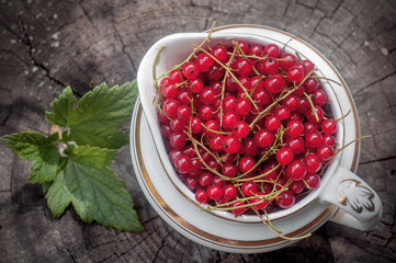 red currant in a vintage bowl on an old wooden background