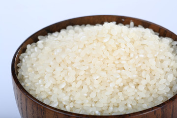 Raw rice in a wooden bowl closeup