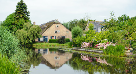 Fototapeta na wymiar Historic Dutch farm reflected in the mirror smooth water surface