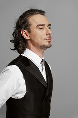 man in white shirt and black vest with long curly hair posing