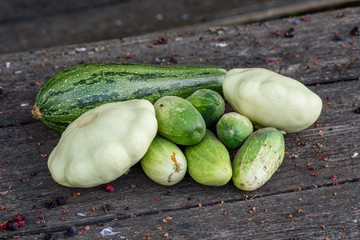 Zucchini, two pattypan squash, few cucumbers harvested from the vegetable garden beds lie on the wooden table