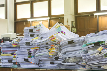 Pile of documents on desk stack up high waiting to be managed.