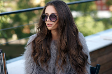 Trendy drssed fashionable girl wearing fur coat. Young pretty beautiful woman with long curly hair...